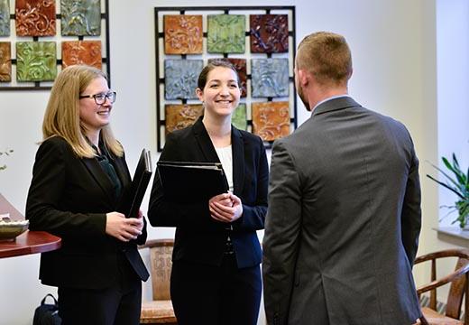 Three students in business attire speak in the Career Center